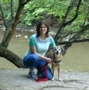 A woman kneeling down next to her dog.