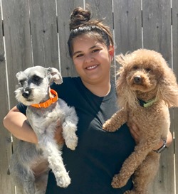 A woman holding two dogs in her arms.