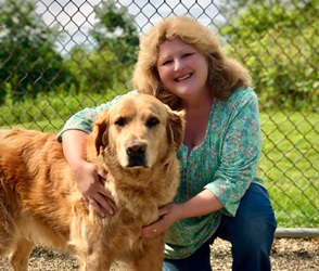 A woman kneeling down next to a dog.