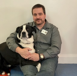 A man sitting on the ground with his dog.