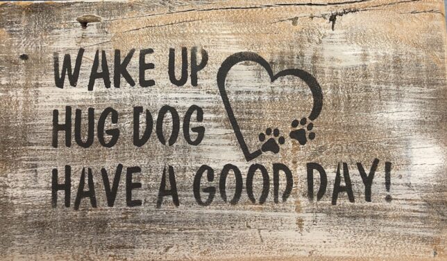 A wooden sign that says wake up big dog have a good day.