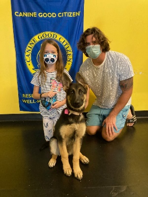 A man and woman with a dog wearing masks.