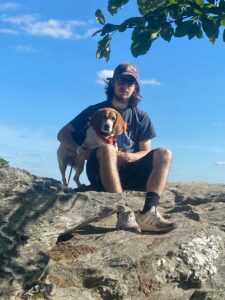 A man and his dog sitting on top of a rock.