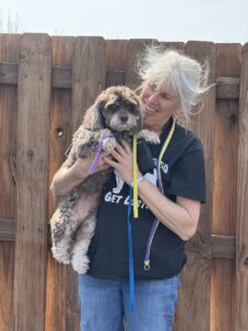 A woman holding a dog with a leash.