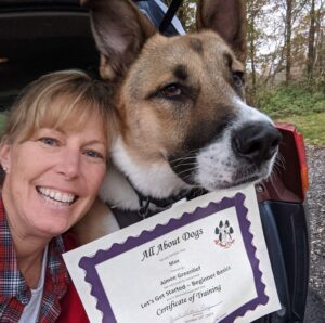 A woman holding a certificate and a dog.