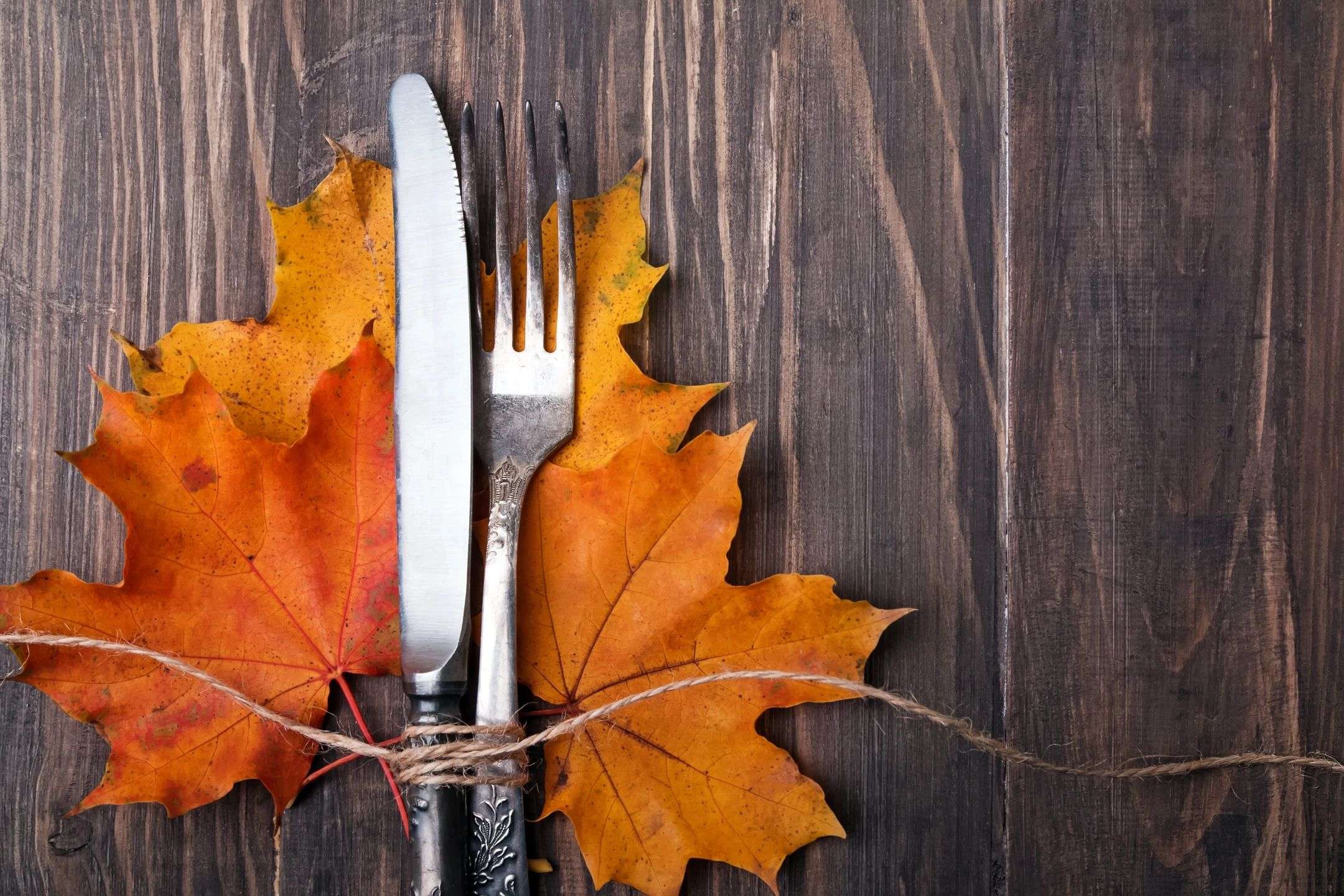 A fork and knife sitting on top of some leaves.