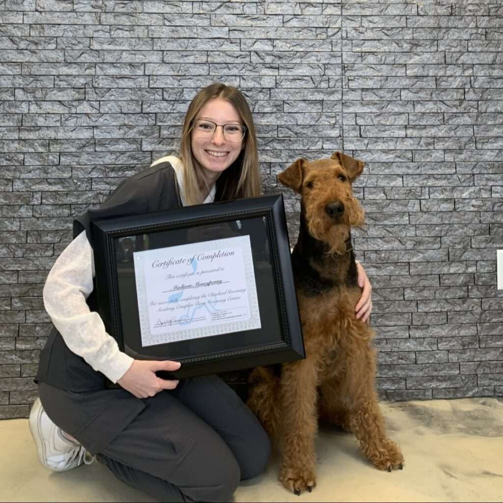 A woman holding a framed certificate with a dog sitting on her lap.