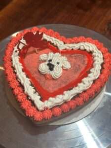 A heart shaped cake with a dog on top of it.