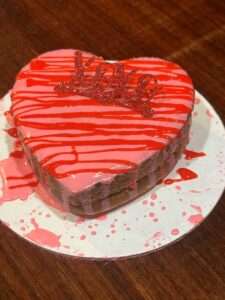 A heart shaped cake with red icing on top of it.